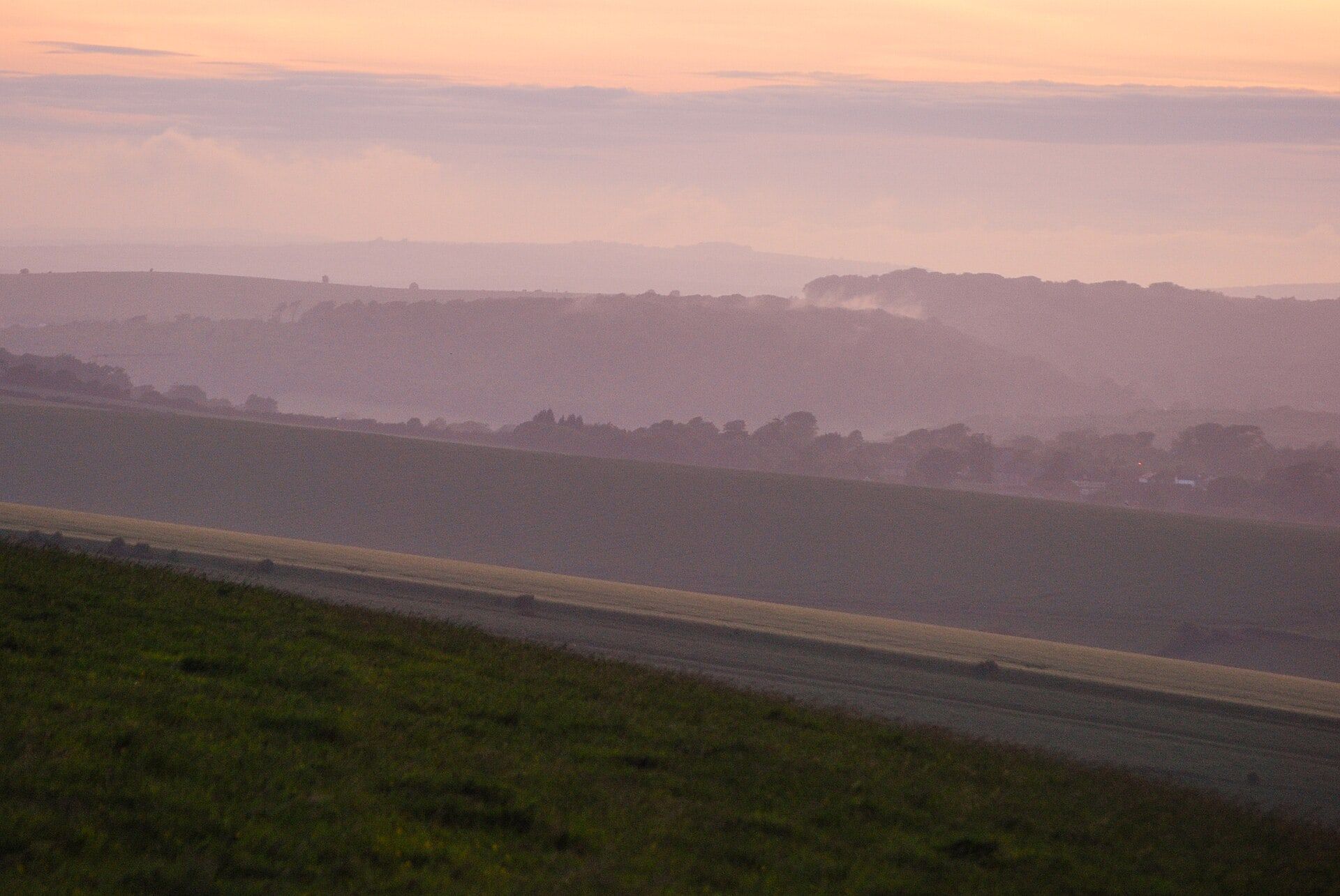 The South Downs near Lewes at dusk, with layers of hills fading into a soft pink sky.